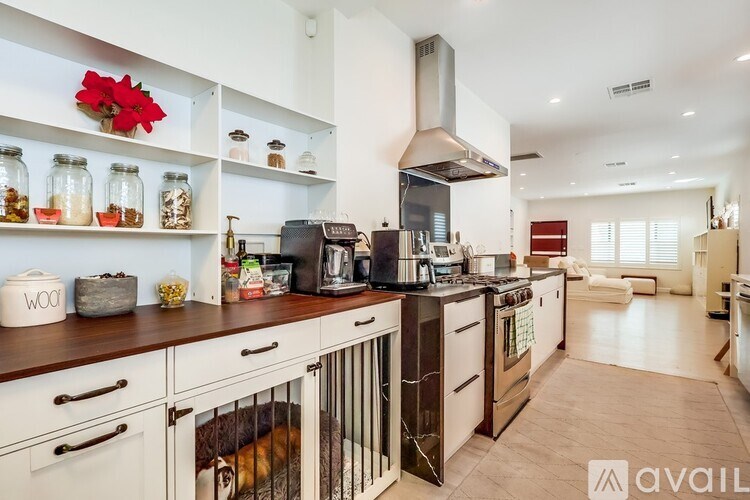 A kitchen with a dog in a crate under the counter.