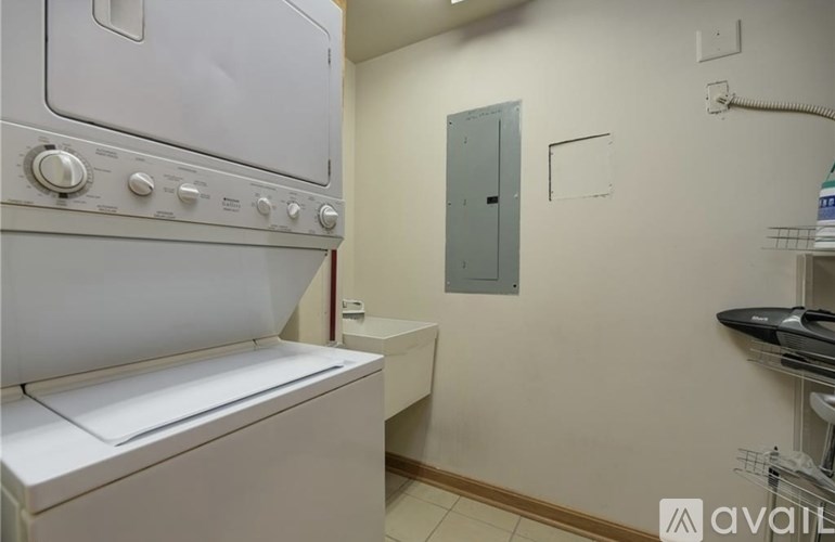 A white washing machine is in a small laundry room with a door and a shelf.