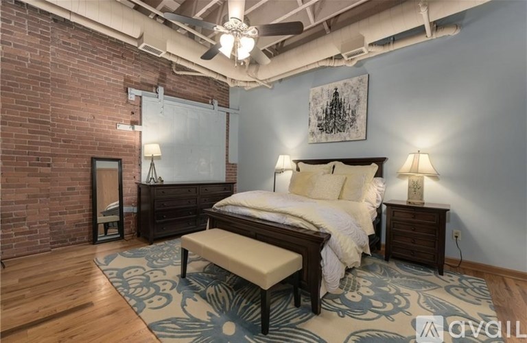 A bedroom with a brick wall and a bed with a wooden headboard.