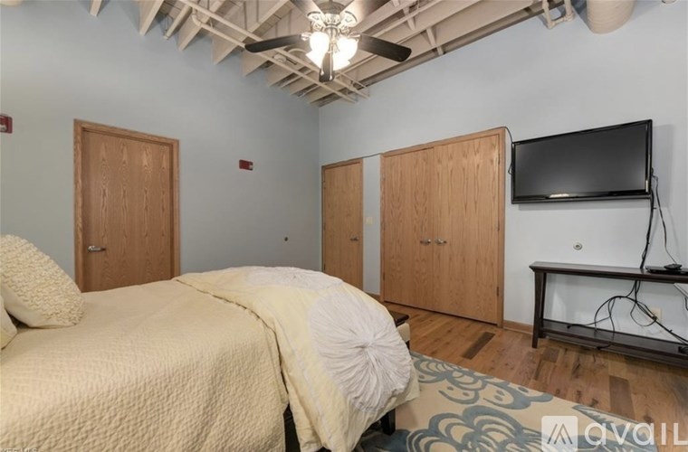 A bedroom with a bed, a television, and two wooden doors.