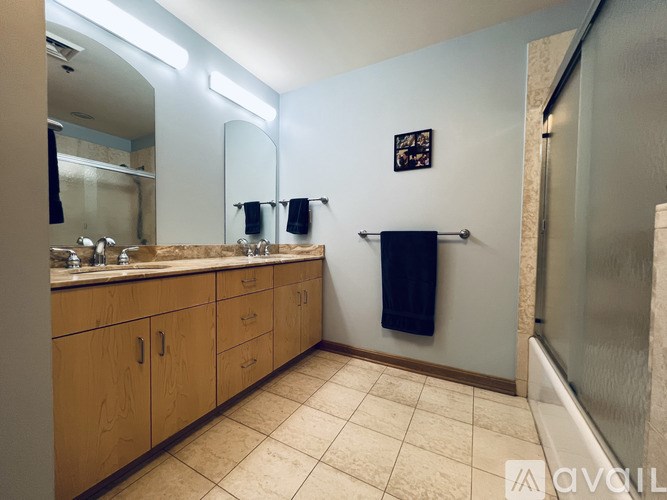 A bathroom with a large mirror, wooden cabinets, and a tiled floor.