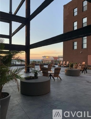 A patio with chairs and tables overlooking a body of water.