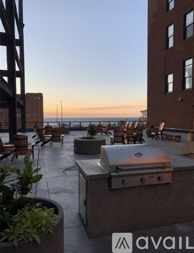 A rooftop patio with a grill and chairs overlooking the water.