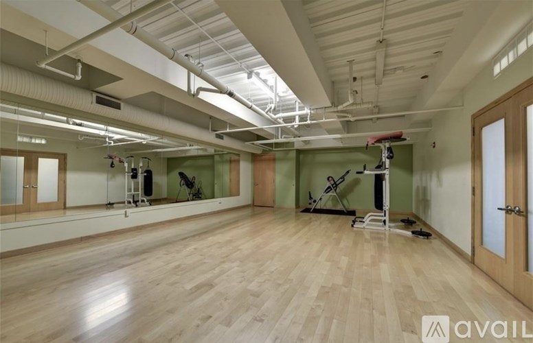 A spacious room with wooden floors and exercise equipment.