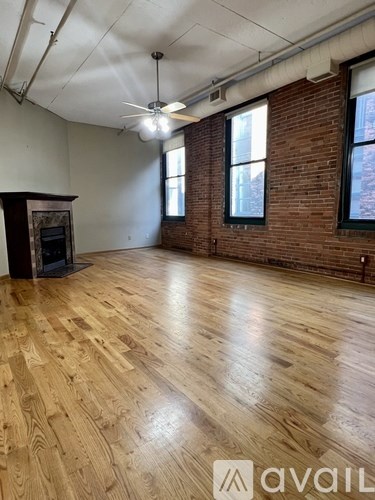 A room with wooden floors and a brick wall.