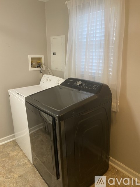 A black dishwasher is in a kitchen with a white dishwasher to its left.