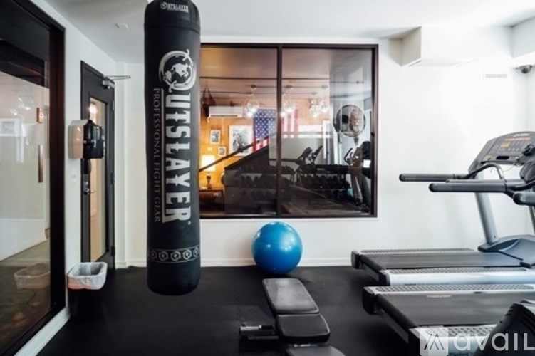 A gym with a treadmill, a blue ball, and a punching bag.