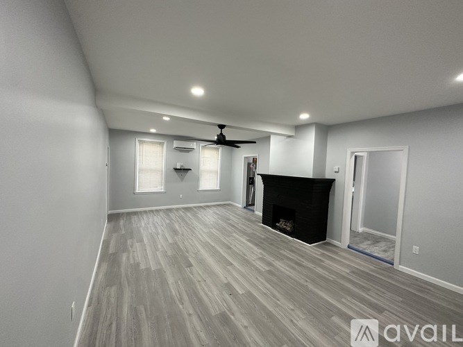 A spacious room with a fireplace and a ceiling fan.