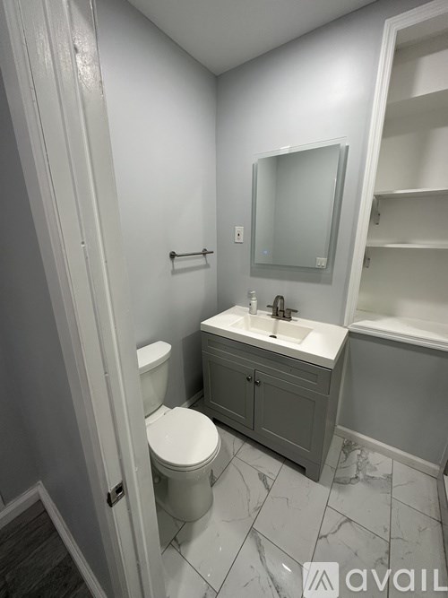 A bathroom with a toilet, sink, and mirror.