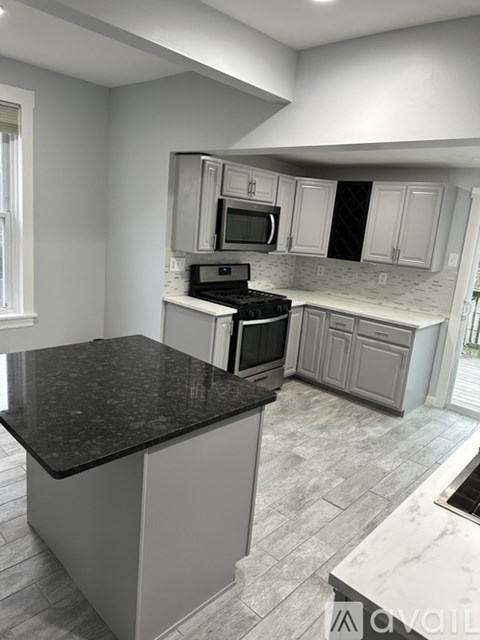 A kitchen with a black countertop and white cabinets.