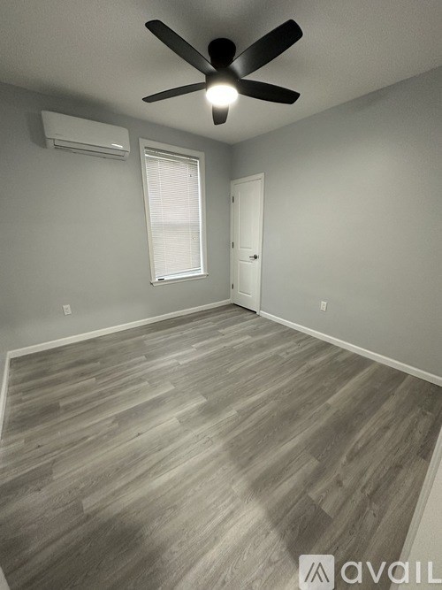 A room with a ceiling fan and wooden flooring.