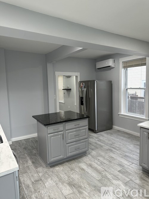 A kitchen with a black countertop and a refrigerator.