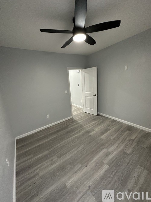 A room with a ceiling fan and a doorway leading to another room.