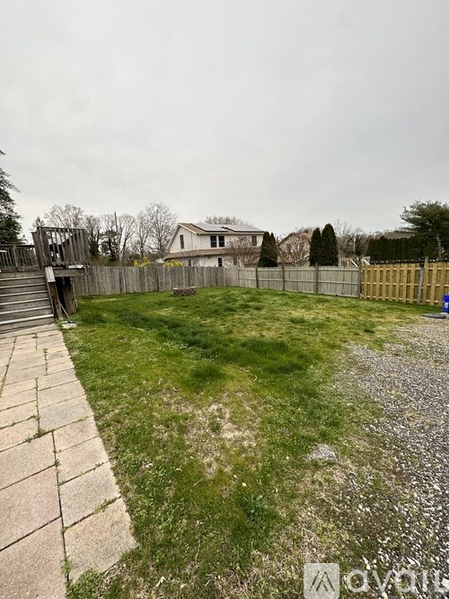 A backyard with a wooden fence and a concrete walkway.