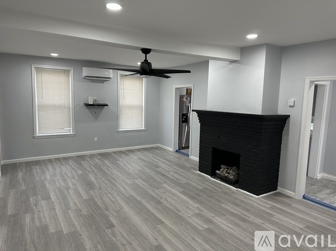 A spacious living room with a fireplace and a ceiling fan.