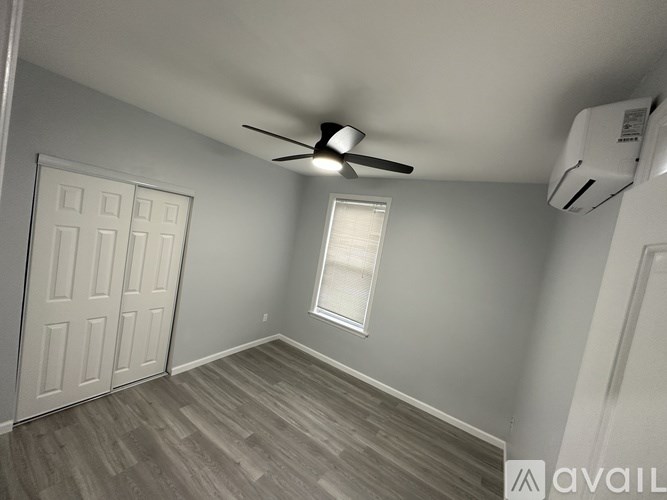 A room with a ceiling fan and a window with blinds.