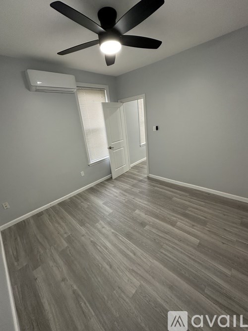 A room with a ceiling fan and wooden flooring.