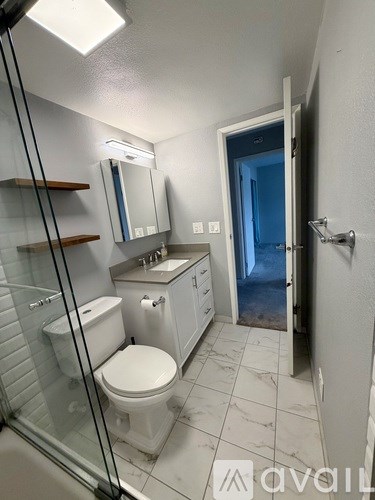 A bathroom with a toilet, sink, mirror, and a walk-in shower.