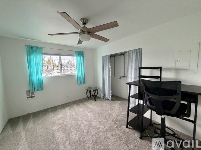 A room with a ceiling fan, a chair, and a desk.
