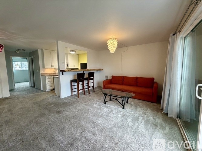 A living room with a grey carpet and a red sofa.