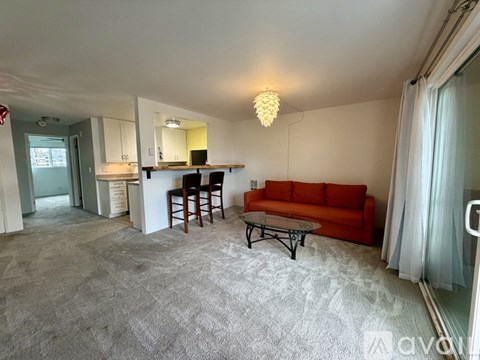 A living room with a grey carpet and a red sofa.
