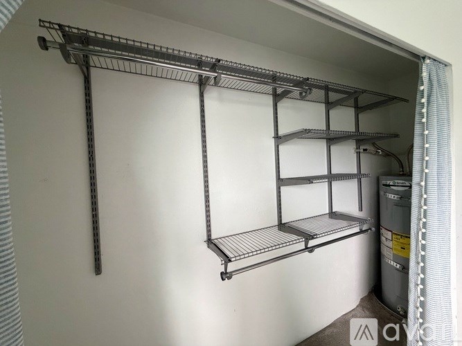 A metal shelving unit with four shelves is mounted on a white wall.