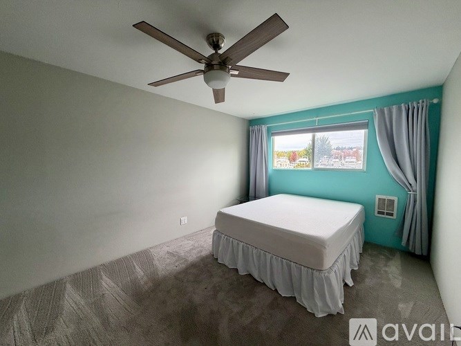 A bedroom with a bed, window, and ceiling fan.