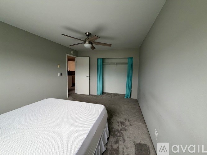 A bedroom with a bed, a ceiling fan, and a door leading to another room.