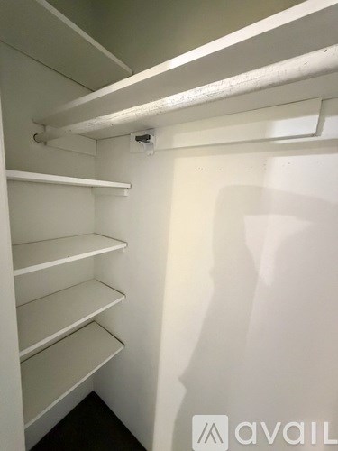 A white closet with a light on the top shelf.