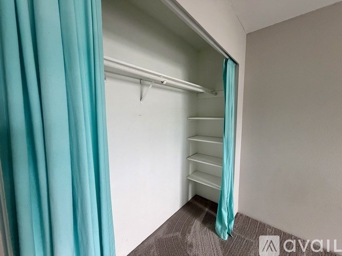 A room with a bed and a window with a blue curtain.