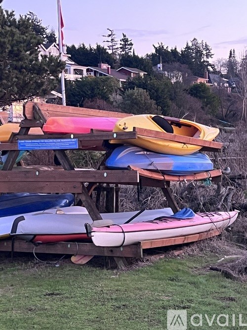 A stack of colorful kayaks are stored on a rack.