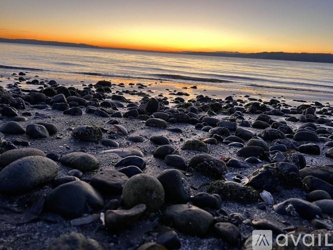 A beach at sunset with pebbles in the foreground.
