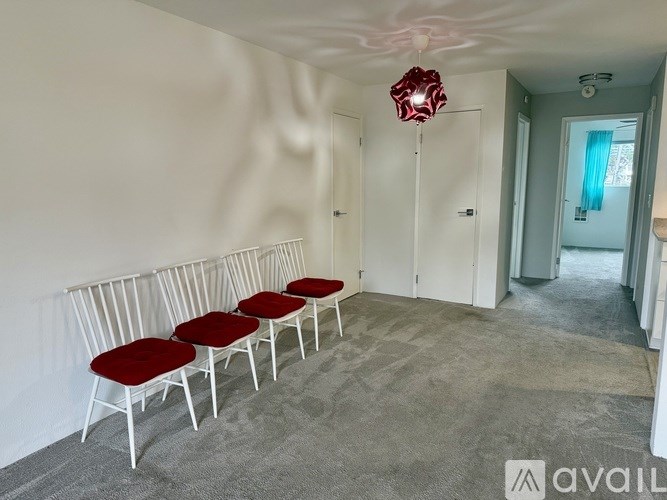 A room with white walls and a row of red chairs.