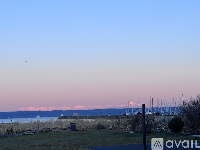 A sign with the word "AVAILABLE" is in the foreground of a coastal scene with boats and mountains in the distance.