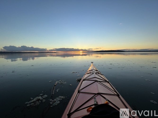 A canoe is on a calm body of water with the sun setting in the distance.