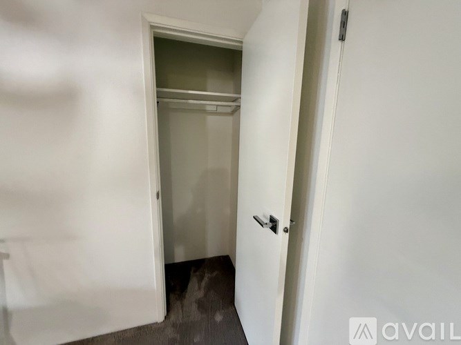 A white door with a glass window is in a white room.