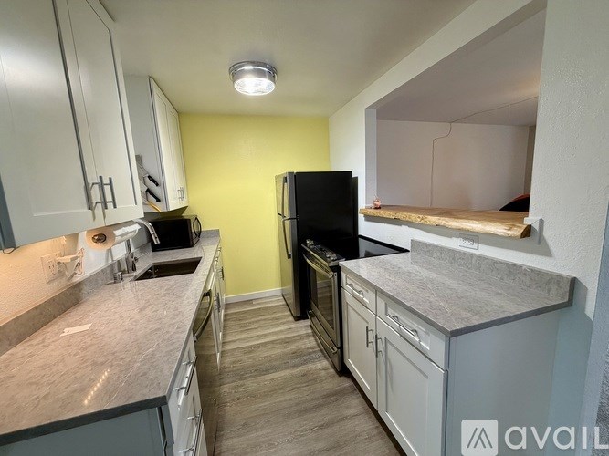 A kitchen with a black refrigerator and white cabinets.
