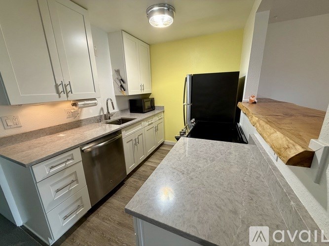 A kitchen with white cabinets and a black refrigerator.