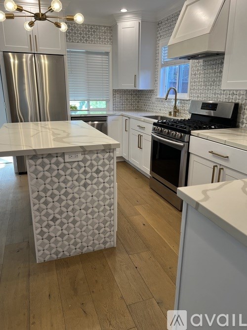 A kitchen with a white marble island and wooden floors.