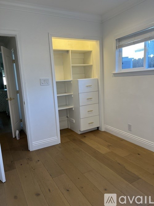 A room with a white door, a white cabinet with drawers, and a window.