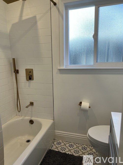 A bathroom with a white tub and a window.