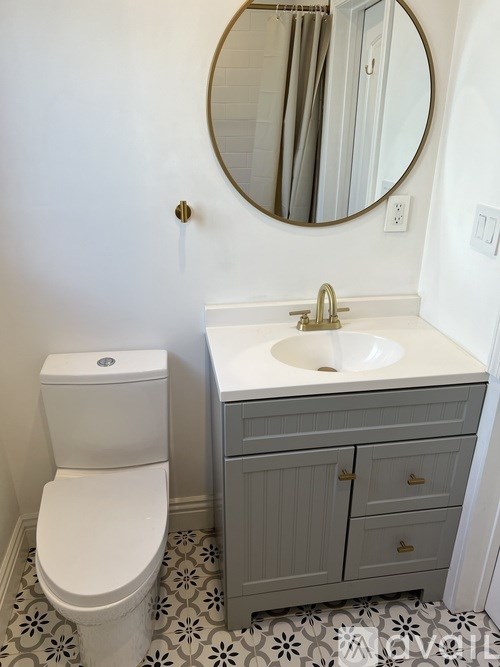A bathroom with a toilet, sink and mirror.