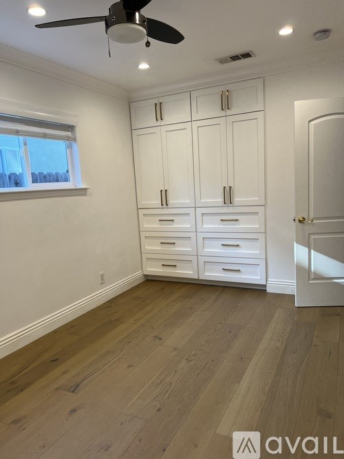 A room with a ceiling fan and wooden flooring.