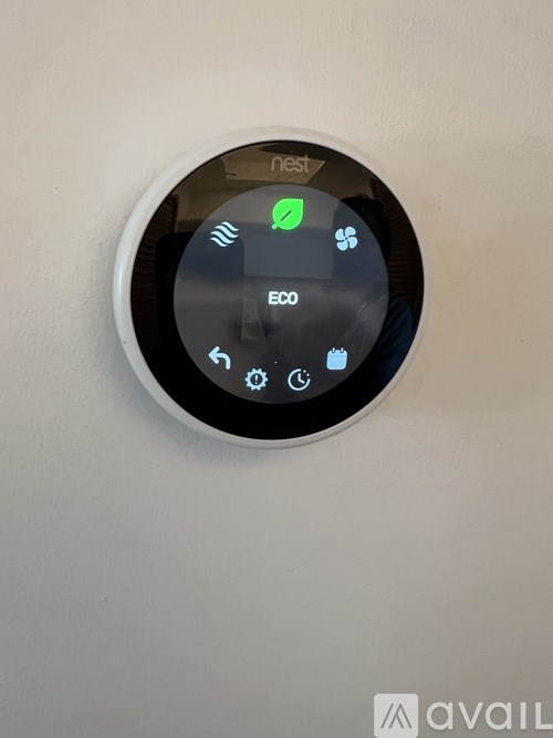 A round device with a green leaf symbol indicating the eco mode is mounted on a wall.