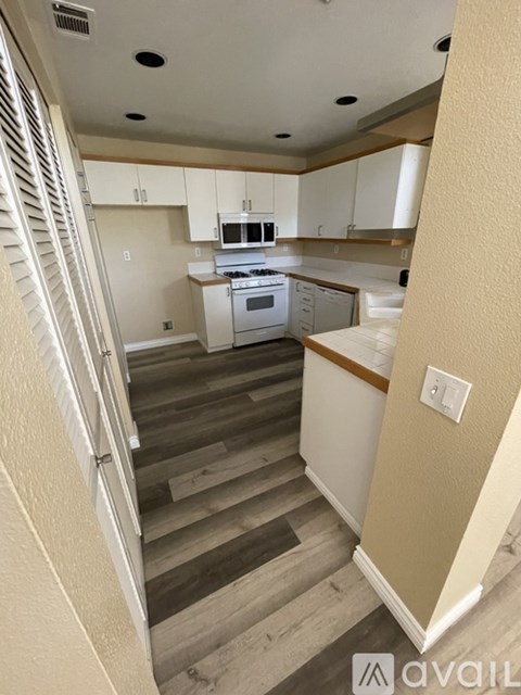 A staircase with a beige wall and wooden steps leads to a kitchen area.