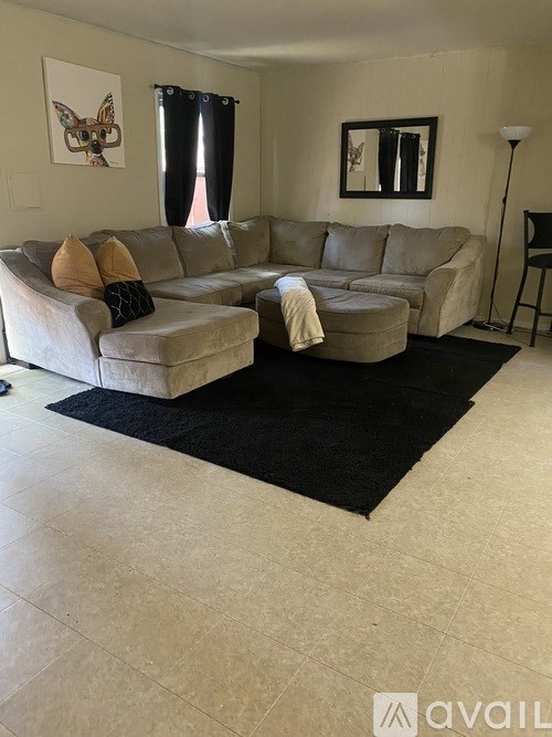 A living room with a large sectional sofa and a rug.
