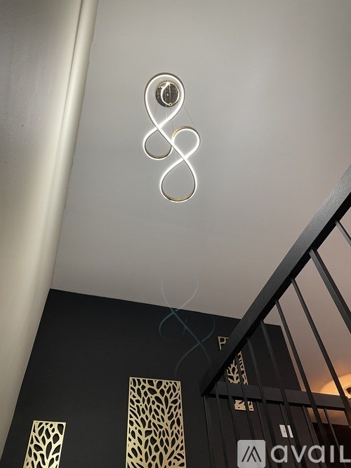 A modern staircase with a black metal railing and a gold patterned wall.