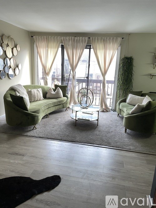 A living room with green couches and a glass table.
