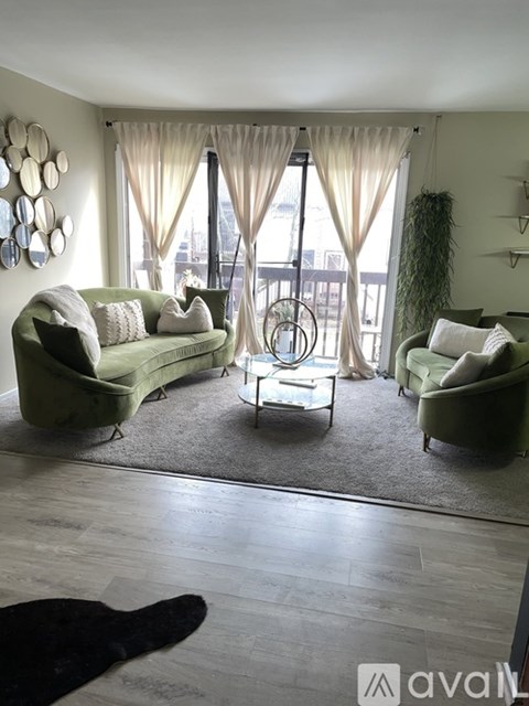 A living room with green couches and a glass table.