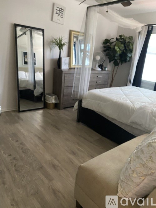 A bedroom with a large bed, a dresser, and a mirror.